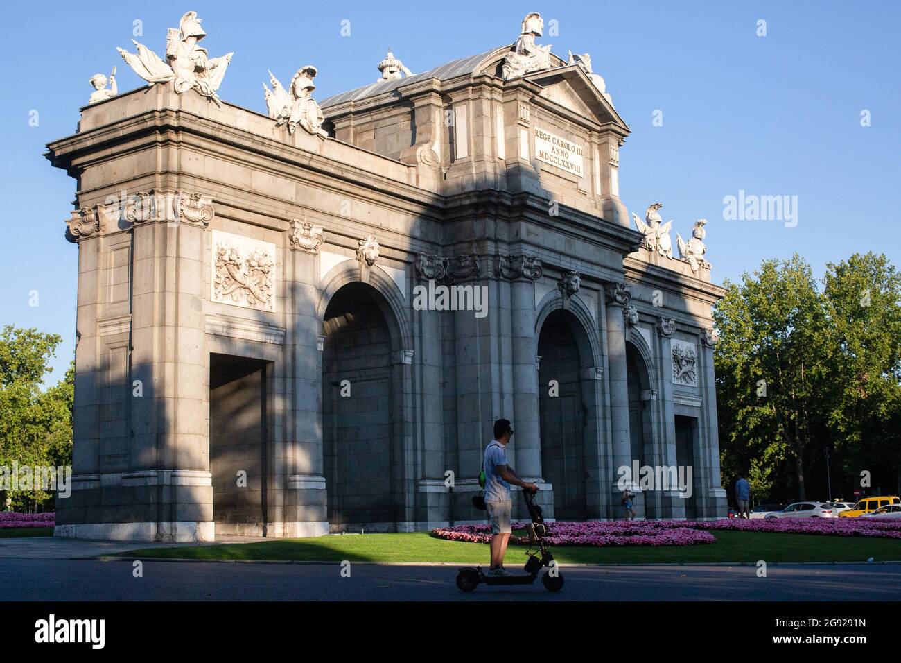Madrid, Spanien. Juli 2021. Ein Mann fährt mit einem Elektroroller vor der  Puerta de Alcalá.am Sonntag, dem 25. Juli 2021, werden der Paseo del Prado  und der Buen Retiro Park in Madrid