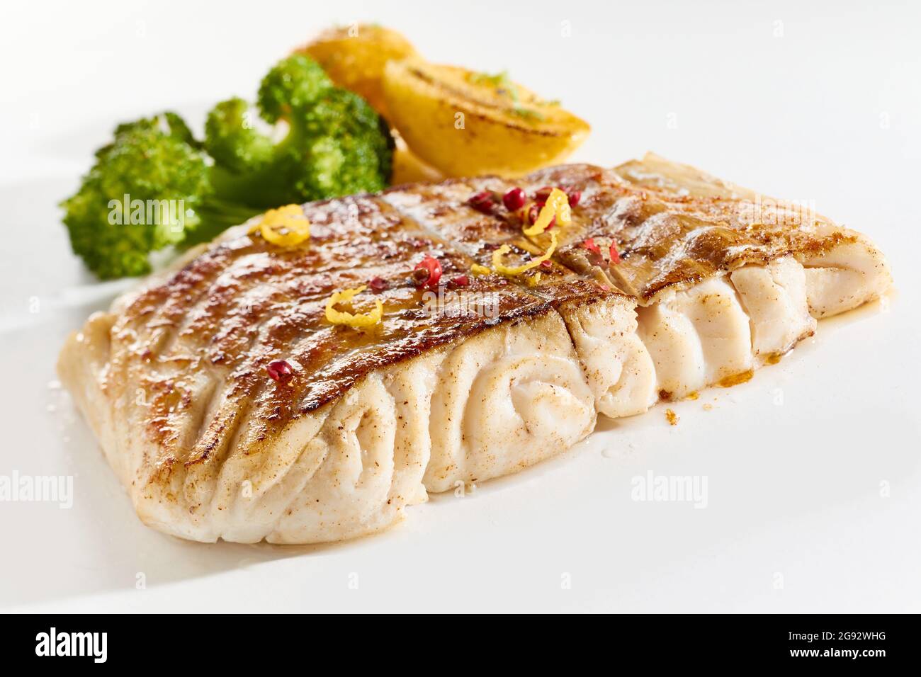 Appetitliche Komposition aus leckeren frittierten Pollack-Fischsteaks und gebratenem Gemüse auf weißer Oberfläche Stockfoto