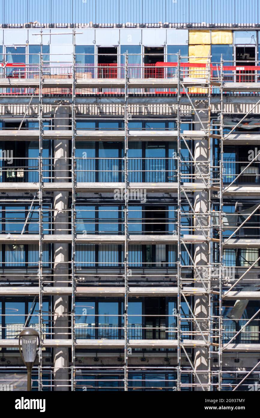 Gerüste ohne Arbeiter auf der Fassade eines Bürogebäudes. Immobilienbau und Renovierungskonzepte Stockfoto