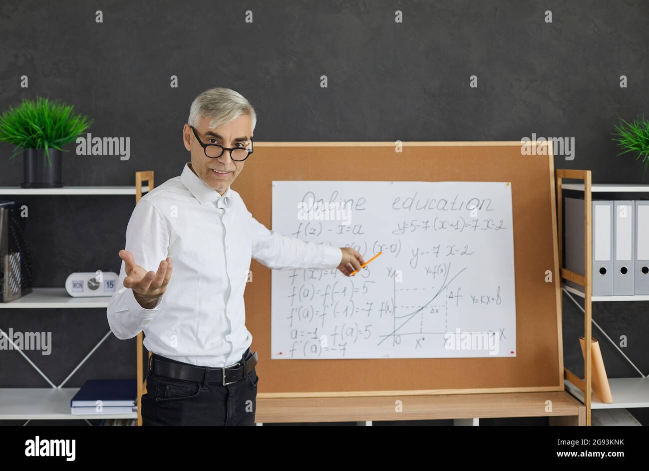 Porträt eines älteren Lehrers, der während des Online-Unterrichts vor dem Klassenzimmer steht Stockfoto