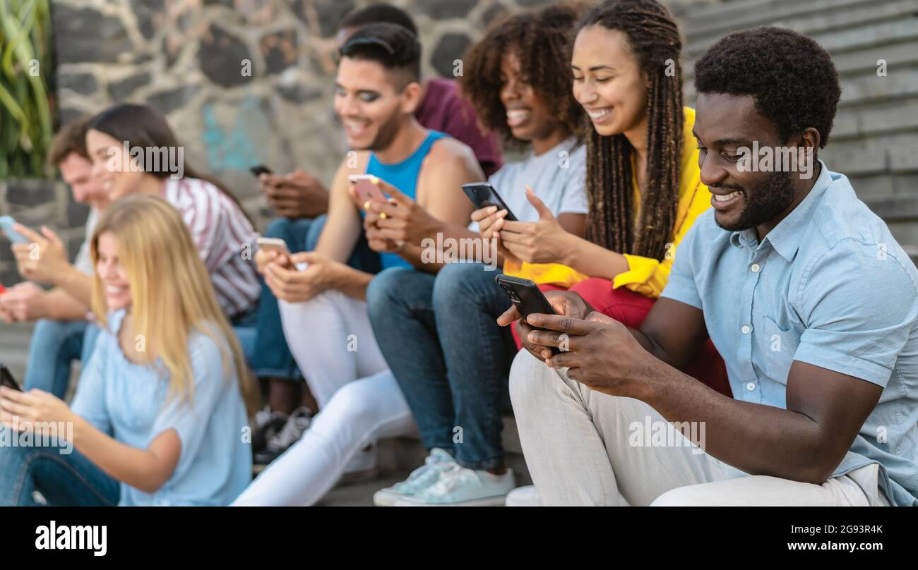 Junge multirassische Gruppe von Freunden mit dem mobilen Smartphone auf der Treppe sitzen - Jugend Millennial Lifestyle-Konzept Stockfoto