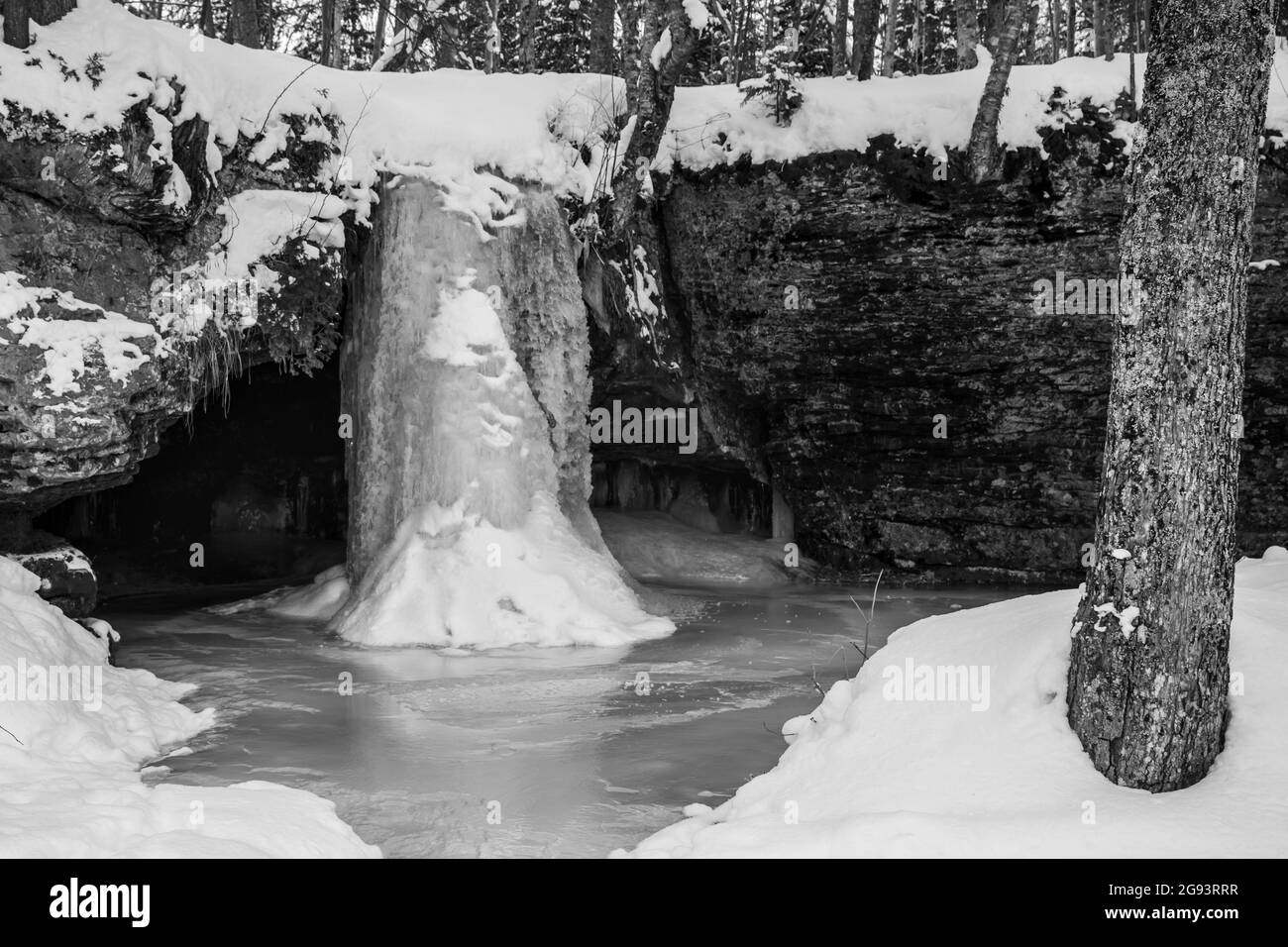 Die gefrorenen Scott Falls fallen etwa 10 Meter über einer Sandsteinklippe in einen kleinen Pool in Munising, Michigan. Stockfoto