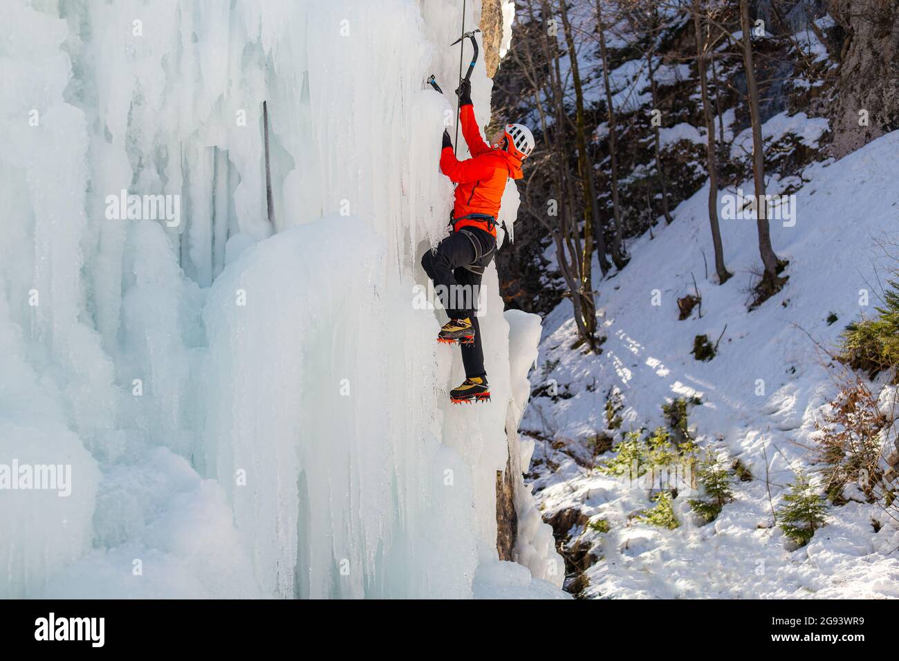 Luftaufnahme eines gefrorenen Wasserfalls und Felsen, bei dem Kletterer seine eisbedeckte Oberfläche mit Eispickeln und Steigeisen aufsteigen Stockfoto