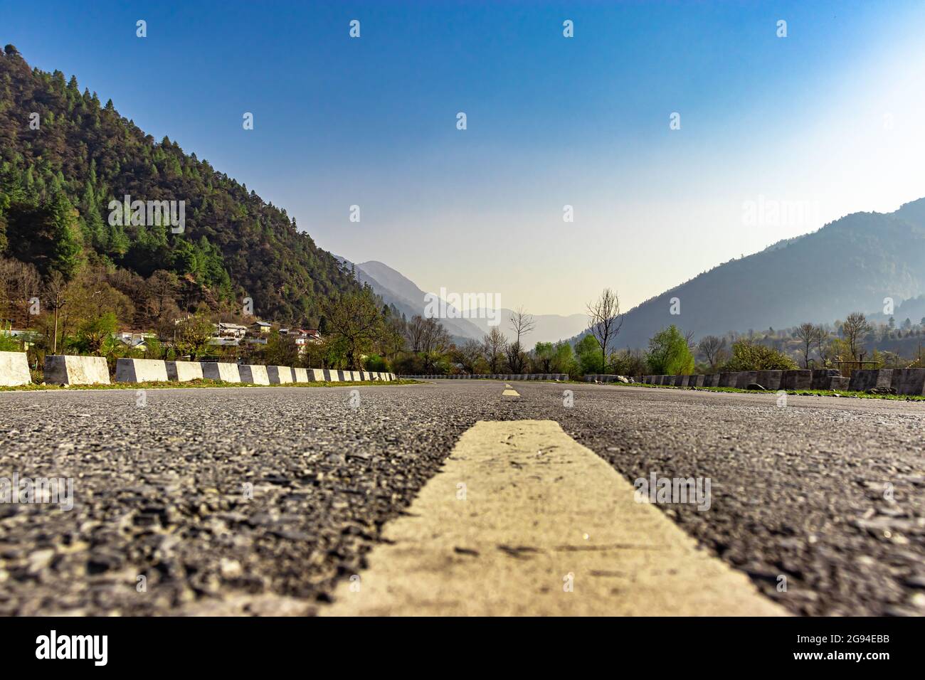 Asphaltstraße, die zum nebligen Bergtal mit blauem Himmel am Morgen aus flachem Winkel Bild führt, wird am shergaon arunachal pradesh india aufgenommen. Stockfoto