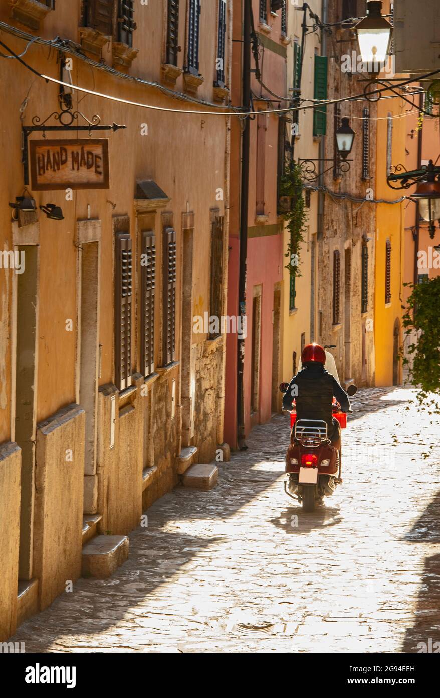 Frau, die in Rovinj auf dem Roller durch die enge Straße fährt Stockfoto