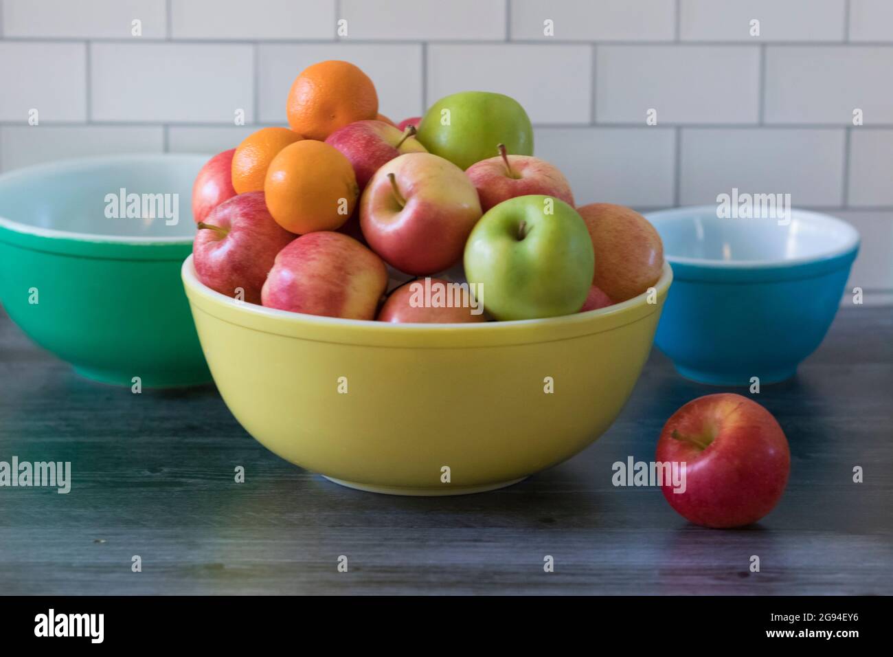Farbige Vintage-Schalen mit Obst in der weißen Küche mit U-Bahn-Fliesen Stockfoto