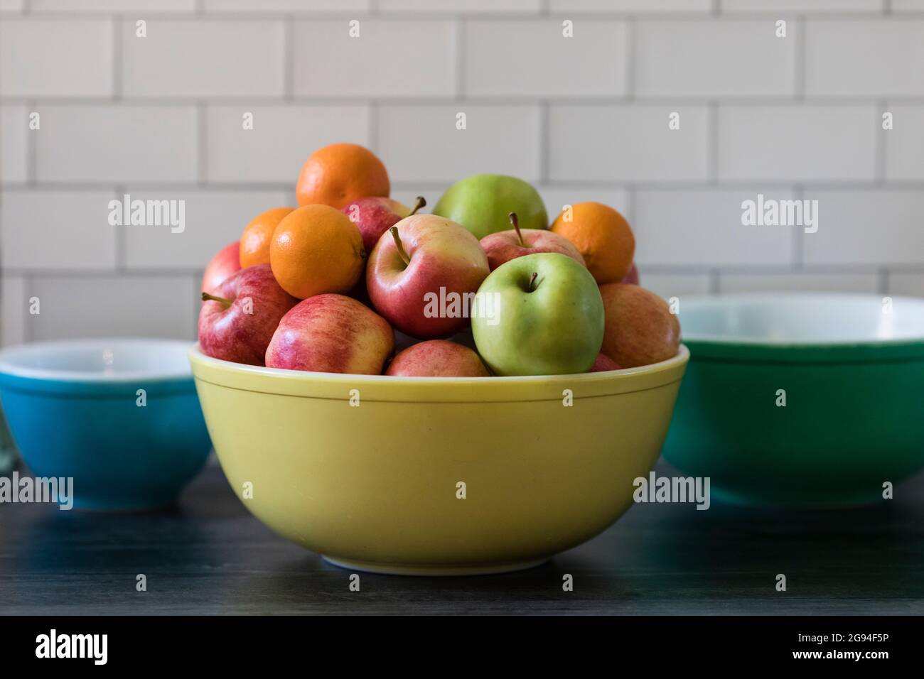 Äpfel und Orangen in der Vintage Fruit Bowl U-Bahn-Fliesenküche Stockfoto