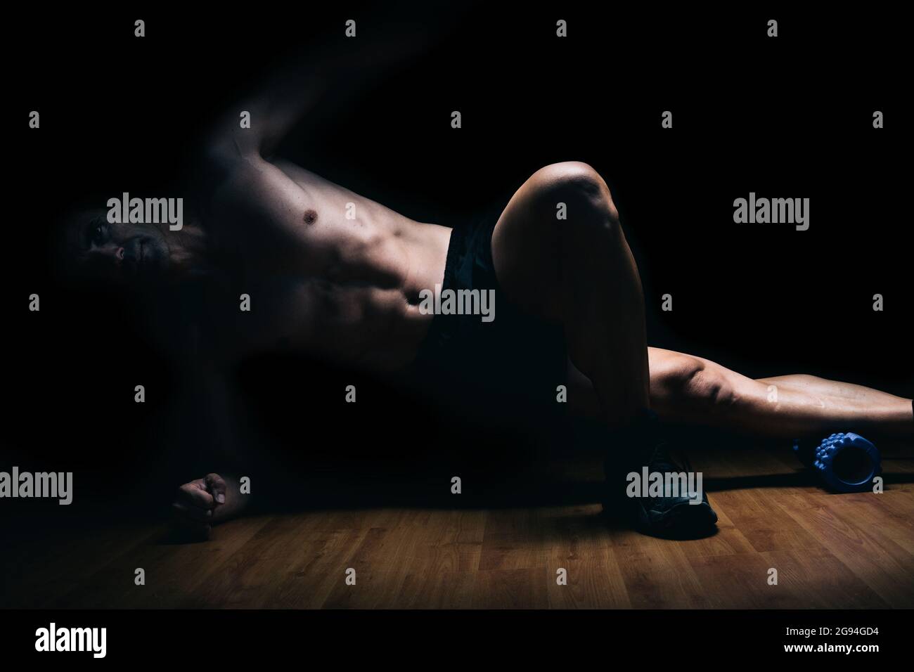 Muskulöser Mann, der auf dem Boden liegt und Stretching-Übungen macht Stockfoto