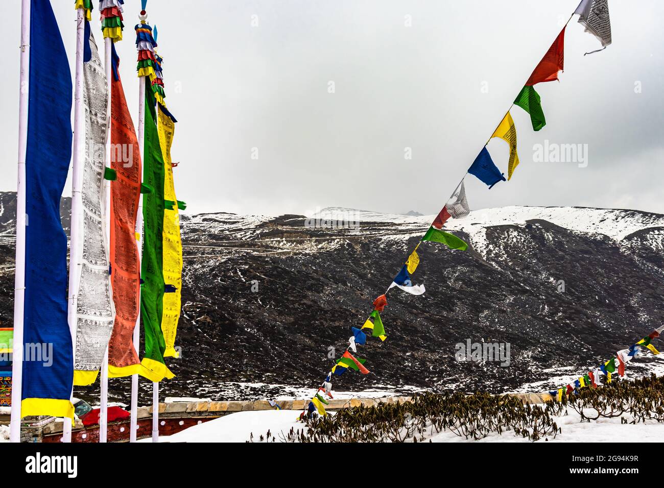 die heilige buddhistische Flagge am Kriegsdenkmal mit schneebedeckten Bergen im Hintergrundbild wurde am jaswant singh Kriegsdenkmal Bumla Pass arunachal pradesh aufgenommen Stockfoto
