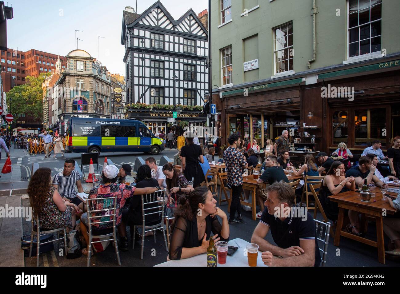 Menschen, die auf Tischen draußen auf der Old Compton Street, Soho, London, Großbritannien, trinken. Stockfoto