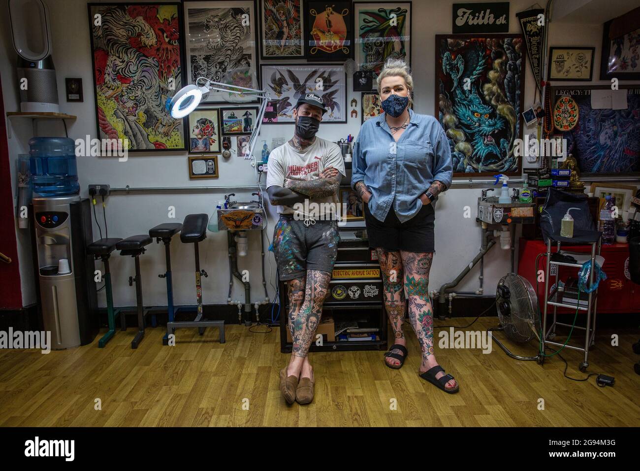 Männliche und weibliche Tattoo-Künstler tragen Gesichtsmaske im Tattoo-Studio Frith Street Tattoo in Soho, London, Großbritannien Stockfoto