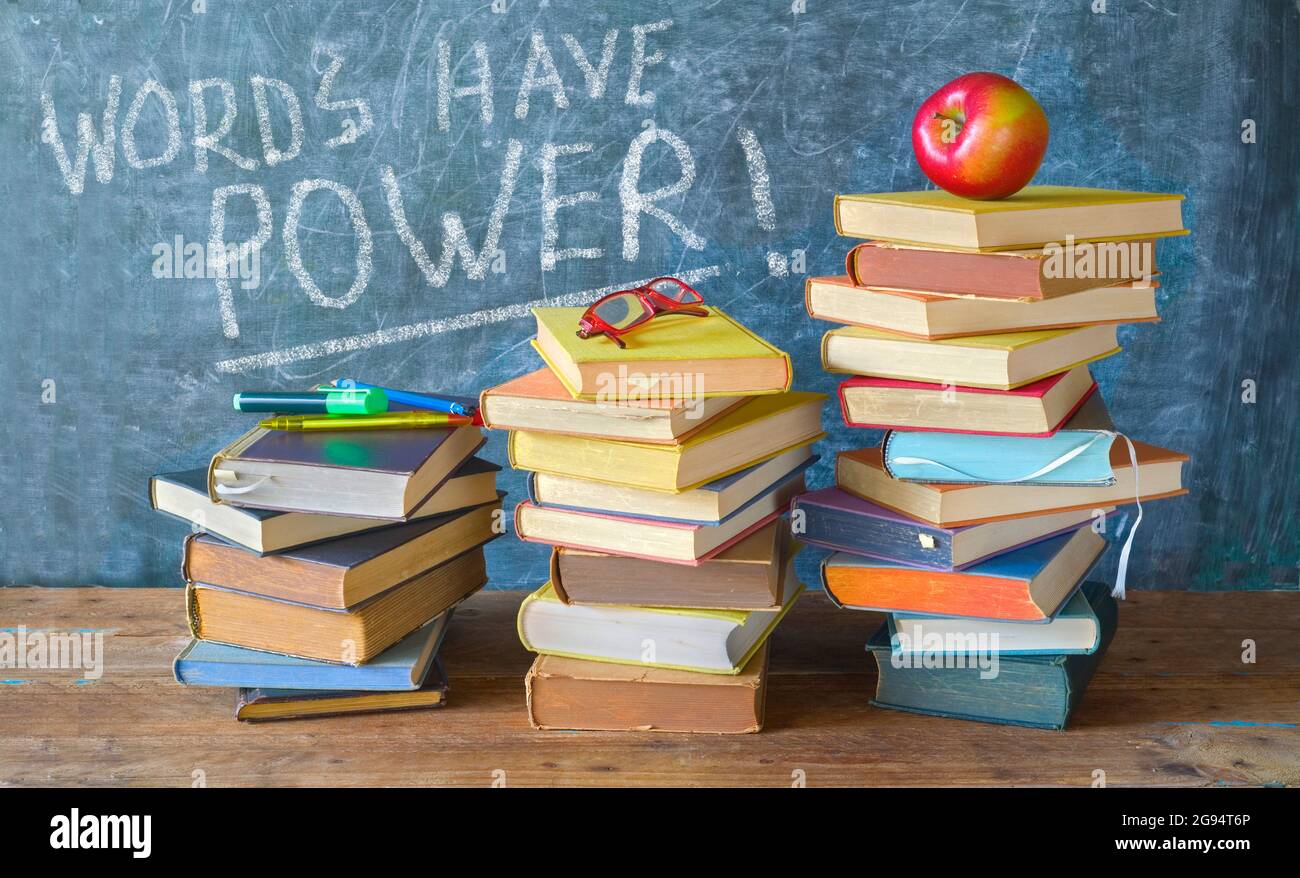 Stapel von Büchern und Beschriftung auf schwarzen Brettern Wörter haben Macht, zurück zur Schule, Bildung Lesen, Lernkonzept Stockfoto