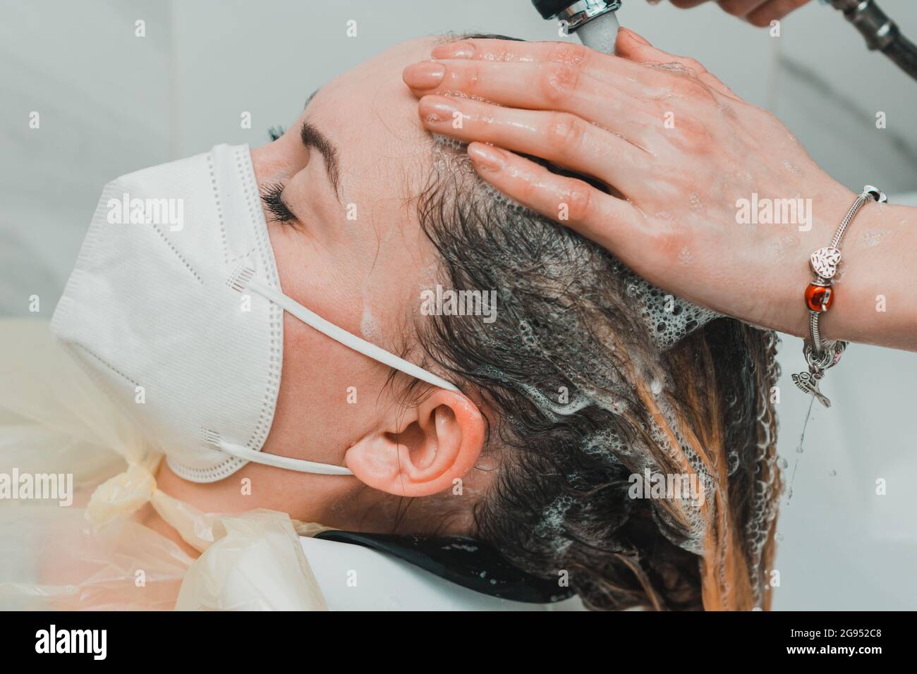 Die Frau in einem Friseurladen färbt ihre Haare und wäscht ihren Kopf während des Färbens ihrer Haare. Neu Stockfoto