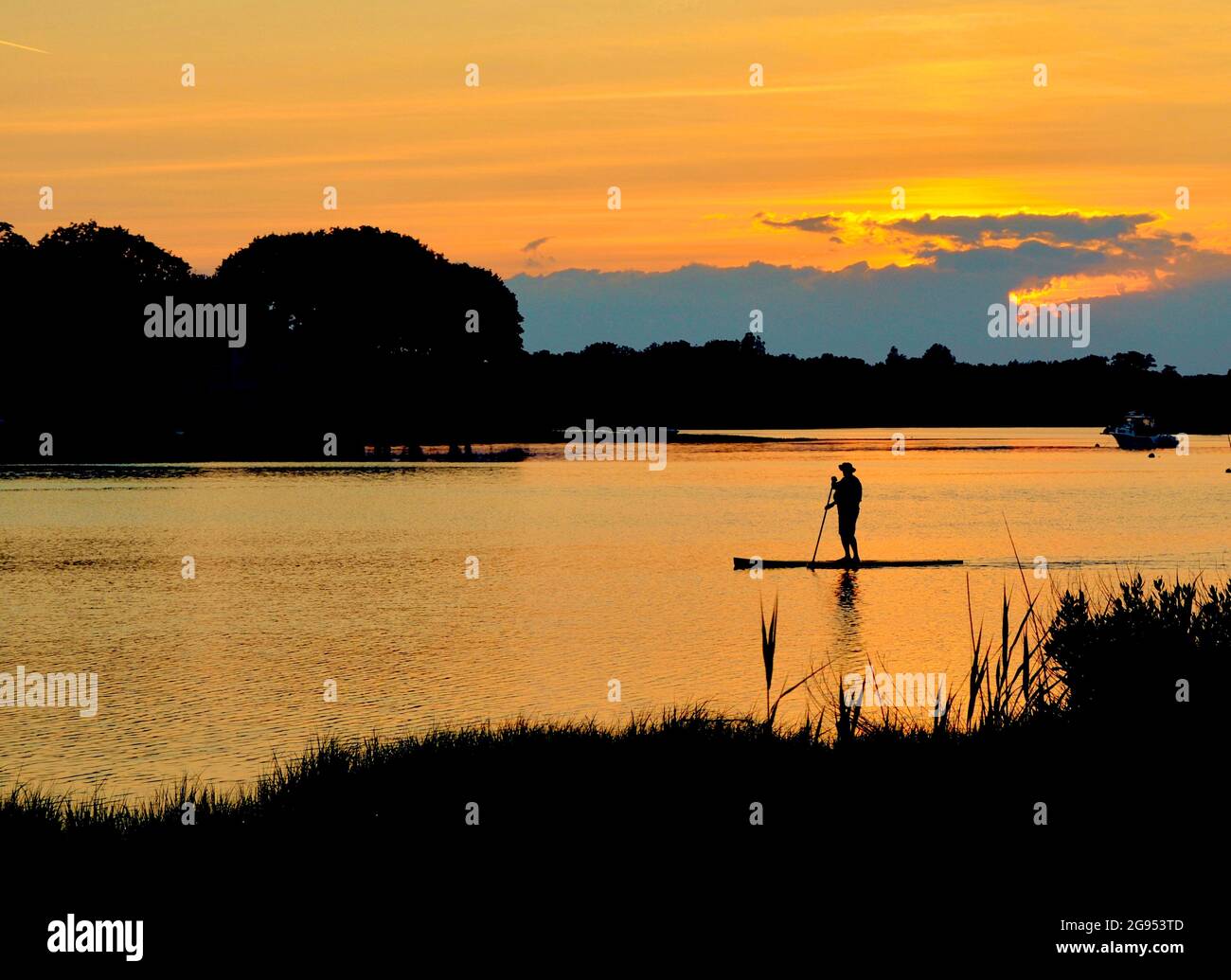 Ein Paddelboarder gleitet bei Sonnenuntergang über die flache Oberfläche eines Long Island Hafens. Speicherplatz kopieren. Stockfoto