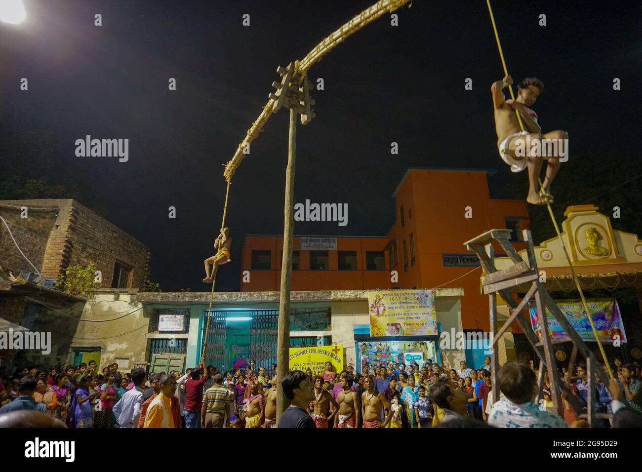 KOLKATA, WESTBENGALEN, INDIEN - 15. APRIL 2018: Zwei hinduistische Anhänger hängen nachts an der Stange in der Luft. Religiöse Sportarten für das Fest genannt Charhak o Stockfoto