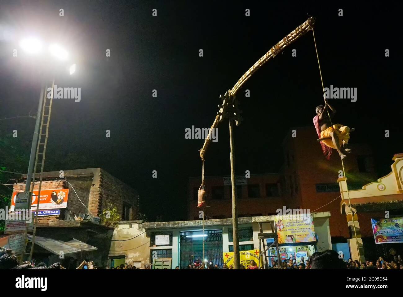 KOLKATA, WESTBENGALEN, INDIEN - 15. APRIL 2018: Zwei hinduistische Anhänger hängen nachts an der Stange in der Luft. Religiöse Sportarten für das Fest genannt Charhak o Stockfoto