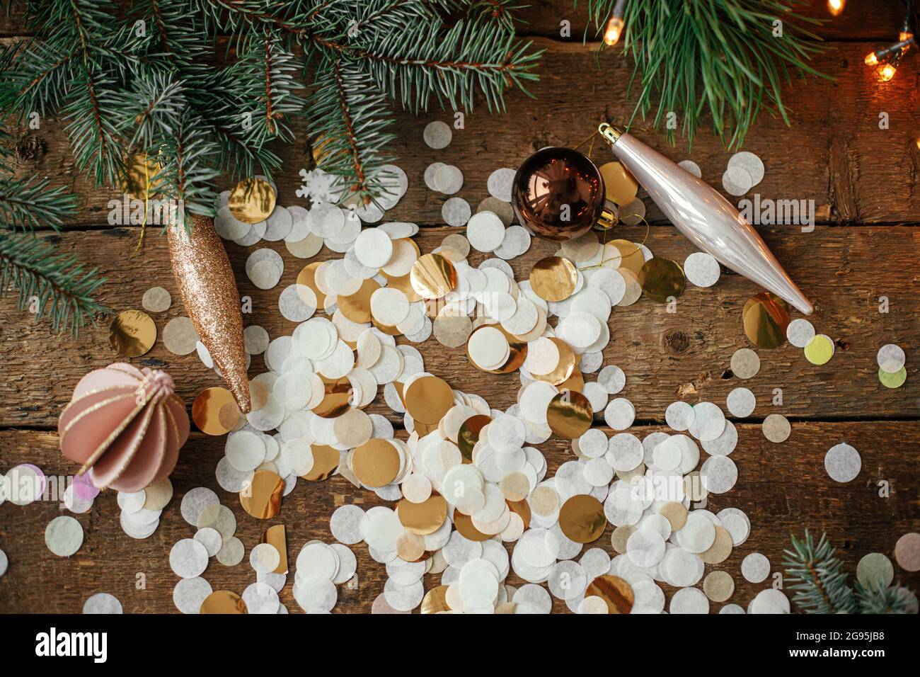 Stilvolle weihnachtsschmuck, Kugeln, goldene Konfetti und Kiefernzweige mit  festlichen Lichtern auf rustikalem Holzhintergrund. Flach liegend. Frohe  Festtagsgrüße Stockfotografie - Alamy