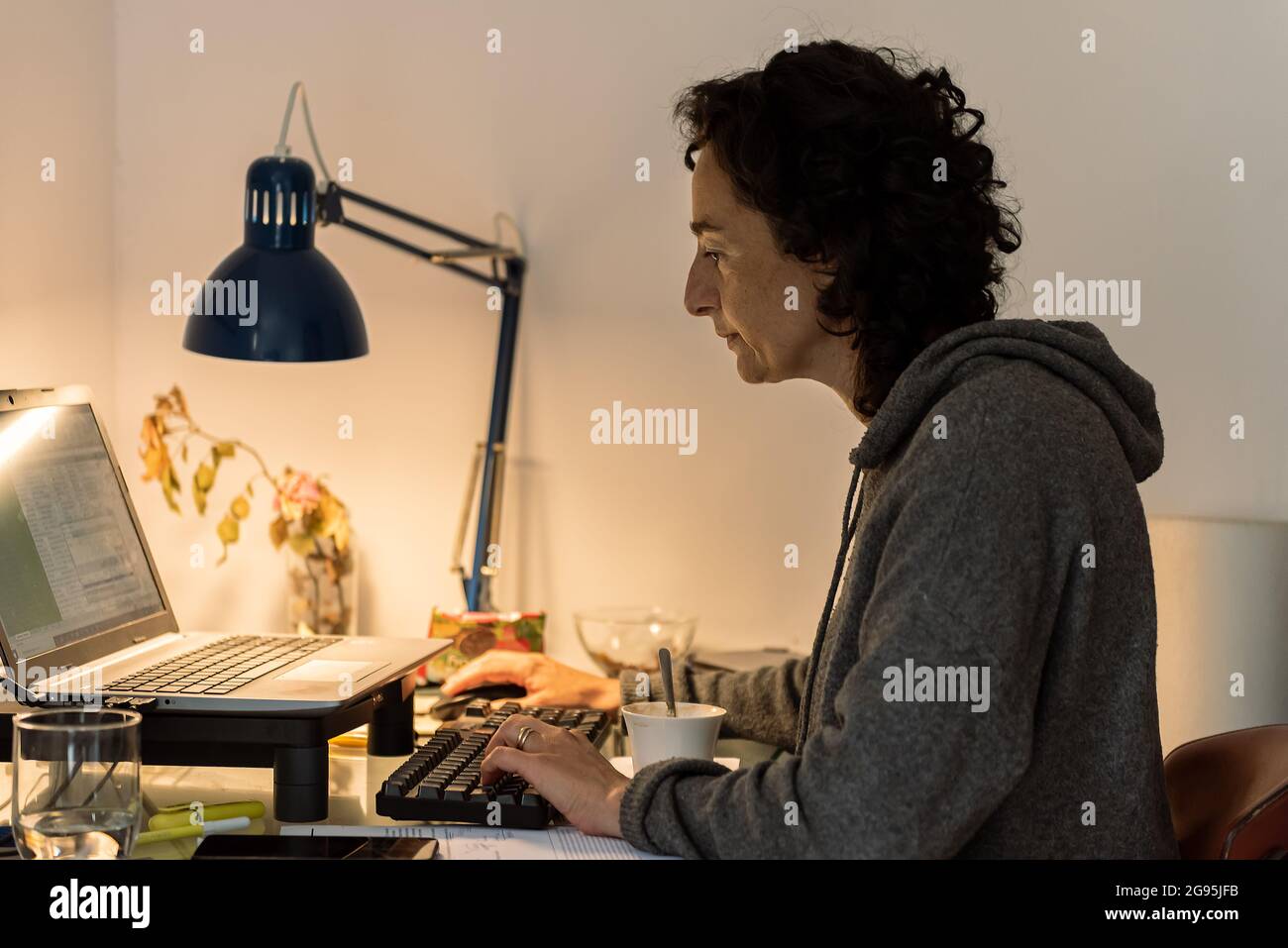 Junge Frau arbeitet online zu Hause mit Computer und weißem Wandhintergrund Stockfoto