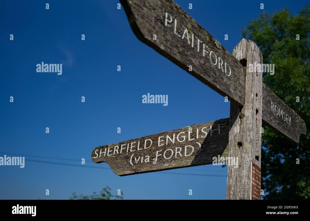 Ein Straßenverkehrsschild aus Holz auf dem Land, das die Wegbeschreibung an einer Kreuzung zu Sherfield English, Plaitford und Romsey in der Grafschaft Hampshire in Großbritannien anzeigt. Stockfoto