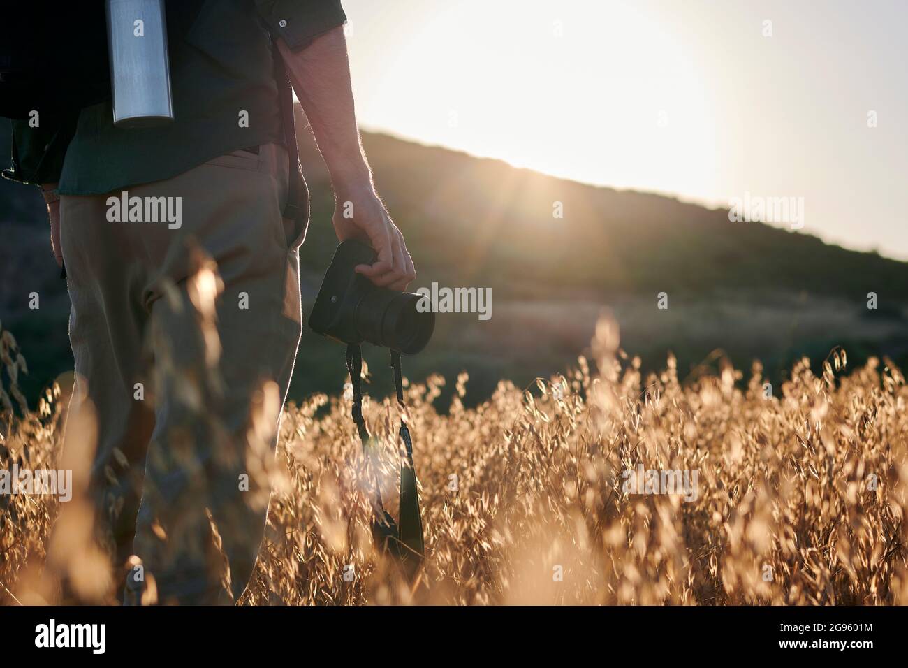 Nahaufnahme eines Fotografen, der bei Sonnenuntergang eine Kamera auf einer Wiese hält Stockfoto