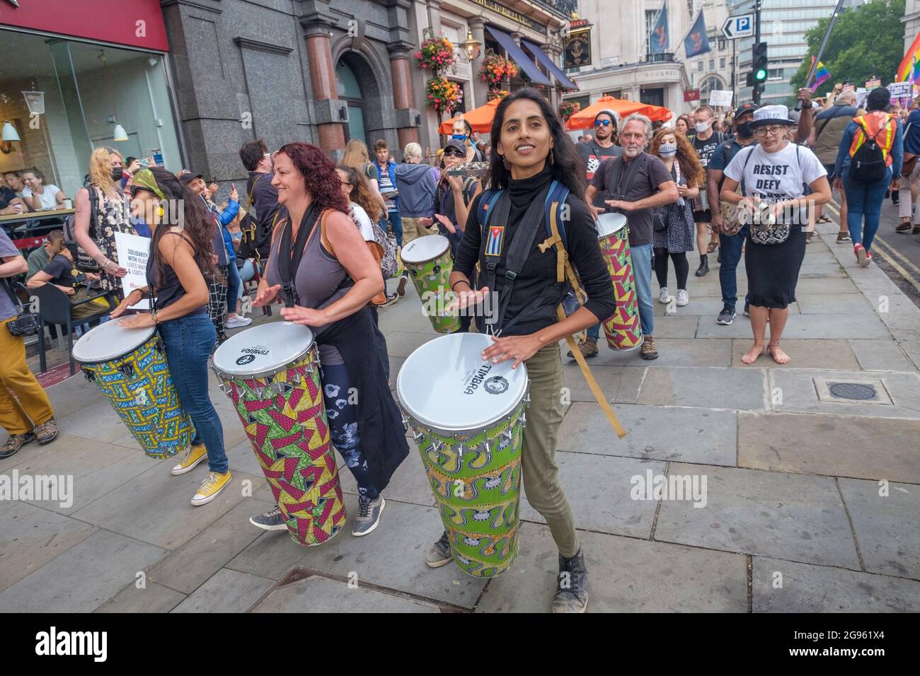 London, Großbritannien. Juli 2012. Brasilianer und Unterstützer marschieren mit einer Samba-Band nach einem Protest vor der brasilianischen Botschaft gegen den Präsidenten Bolsonaro, der derzeit wegen seines Misshandlens der Pandemie in einer rechtlichen Untersuchung steht, in Richtung Whitehall. Sie fordern Nahrungsmittel und Impfstoffe für alle, die Achtung der indigenen Rechte und des Landes, ein Ende der Polizeigewalt und der Tötung schwarzer Menschen, und fordern ein Ende seiner frauenfeindlichen, arbeiterfeindlichen und schwulenfeindlichen Regierung und ihres Angriffs auf Wissenschaft, Bildung und Kultur. Peter Marshall/Alamy Live News Stockfoto