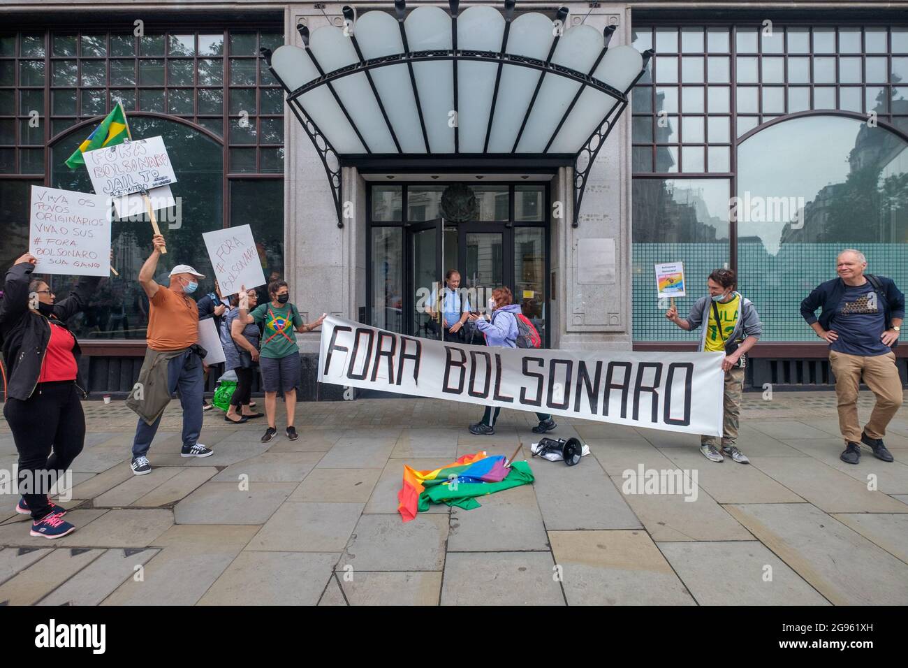 London, Großbritannien. Juli 2012. Späte Ankünfte halten vor der brasilianischen Botschaft ein Transparent mit dem Titel „Fora Bolsonaro“ (Bolsonaro raus). Präsident Bolsonaro befindet sich derzeit wegen seiner Misshandlung der Pandemie in einer rechtlichen Untersuchung. Sie fordern Nahrungsmittel und Impfstoffe für alle, die Achtung der indigenen Rechte und des Landes, ein Ende der Polizeigewalt und der Tötung schwarzer Menschen, und fordern ein Ende seiner frauenfeindlichen, arbeiterfeindlichen und schwulenfeindlichen Regierung und ihres Angriffs auf Wissenschaft, Bildung und Kultur. Peter Marshall/Alamy Live News Stockfoto