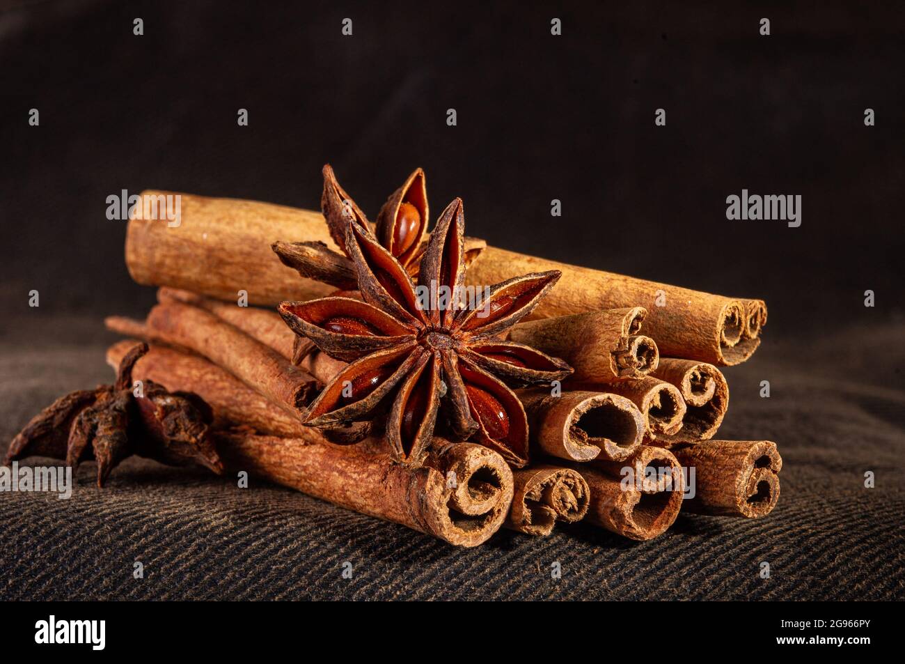 Weihnachtliche Backwürze, Zimtstangen und Anissterne für Weihnachtskuchen, Kekse oder Glühwein auf schwarzem Hintergrund, Makrofoto. Stockfoto