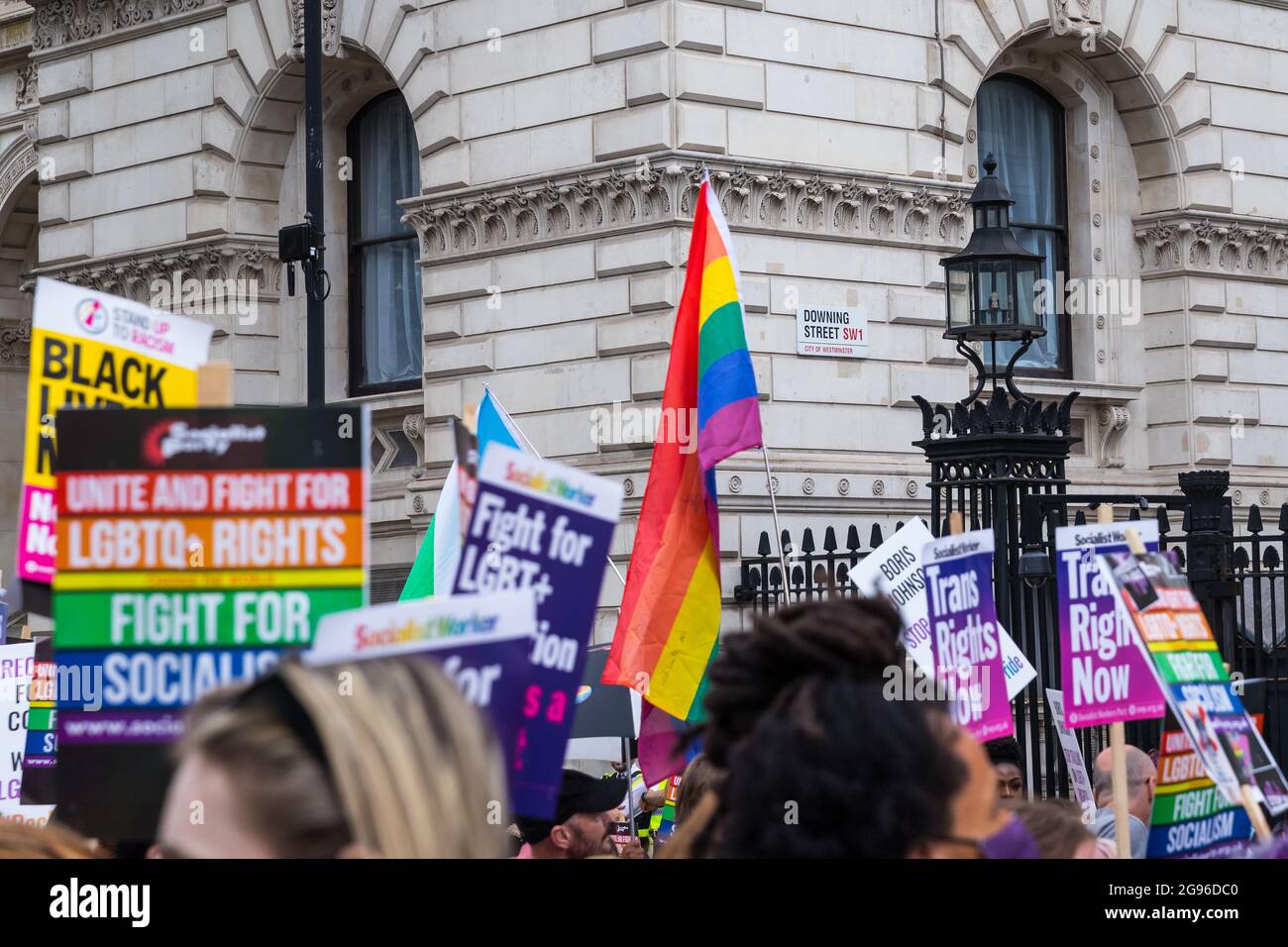 Regenbogenfahne und Plakate mit dem Downing Street Schild im Hintergrund, während des Reclaim Pride Protests, London, organisiert von Peter Tatchell Stockfoto