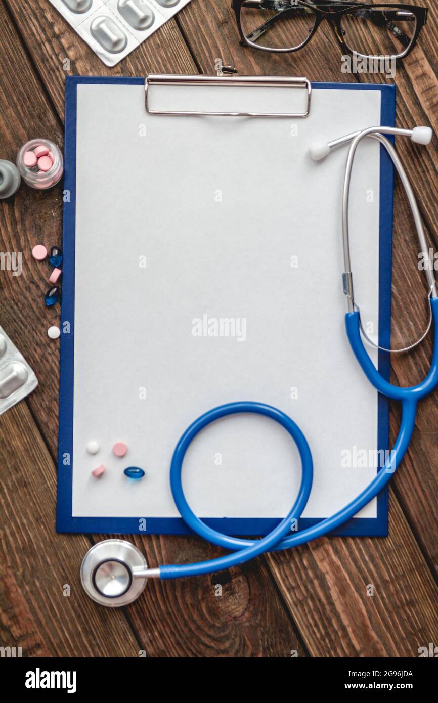 Nahaufnahme der Krankenkarte des Patienten, Stethoskop und Pillen auf dem Arzttisch Stockfoto