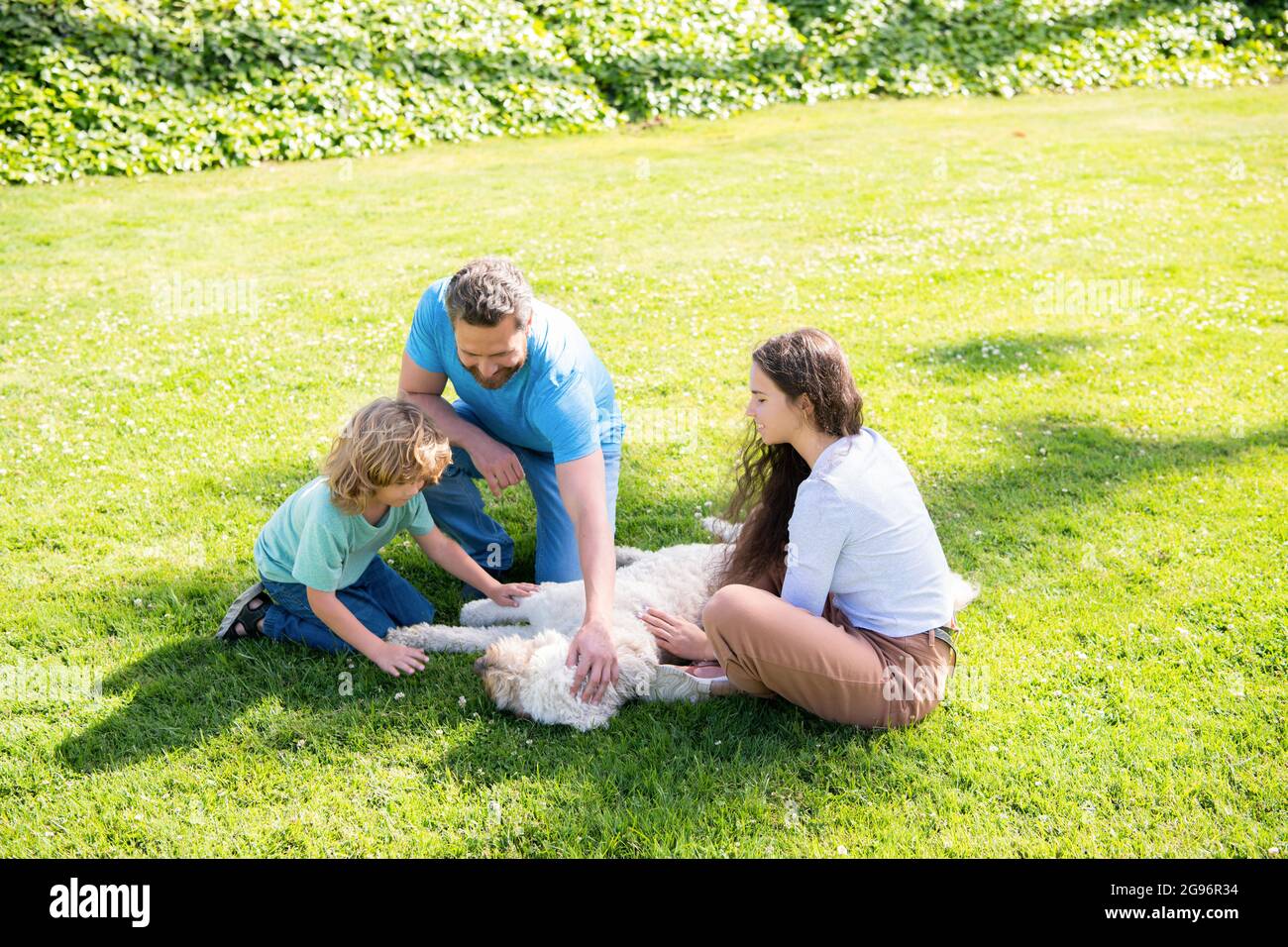 Familientag. Freundschaft. Vater Mutter und Kind auf grünem Parkgras. Freundliche Familie mit Haustier. Stockfoto
