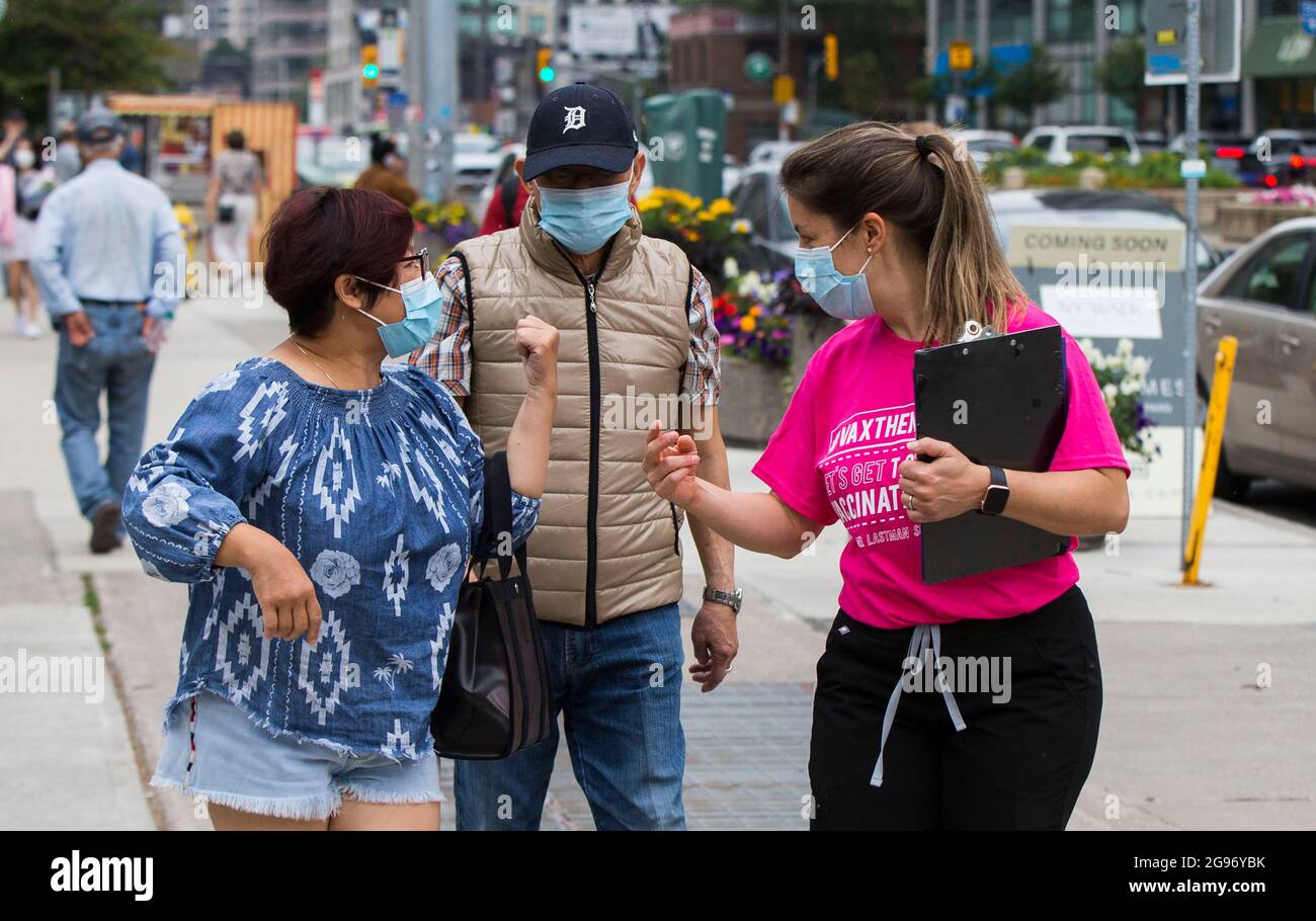 Toronto, Kanada. Juli 2021. Ein Mitarbeiter (R) lädt am 24. Juli 2021 Personen ein, sich auf einer Straße in der Nähe einer Impfklinik am Mel Lastman Square in Toronto, Kanada, impfen zu lassen. Die Stadt Toronto hat hier am Samstag eine wochenlange Impfklinik eröffnet, in der Personen ab 12 Jahren zu den COVID-19-Impfungen willkommen geheißen wurden. Quelle: Zou Zheng/Xinhua/Alamy Live News Stockfoto