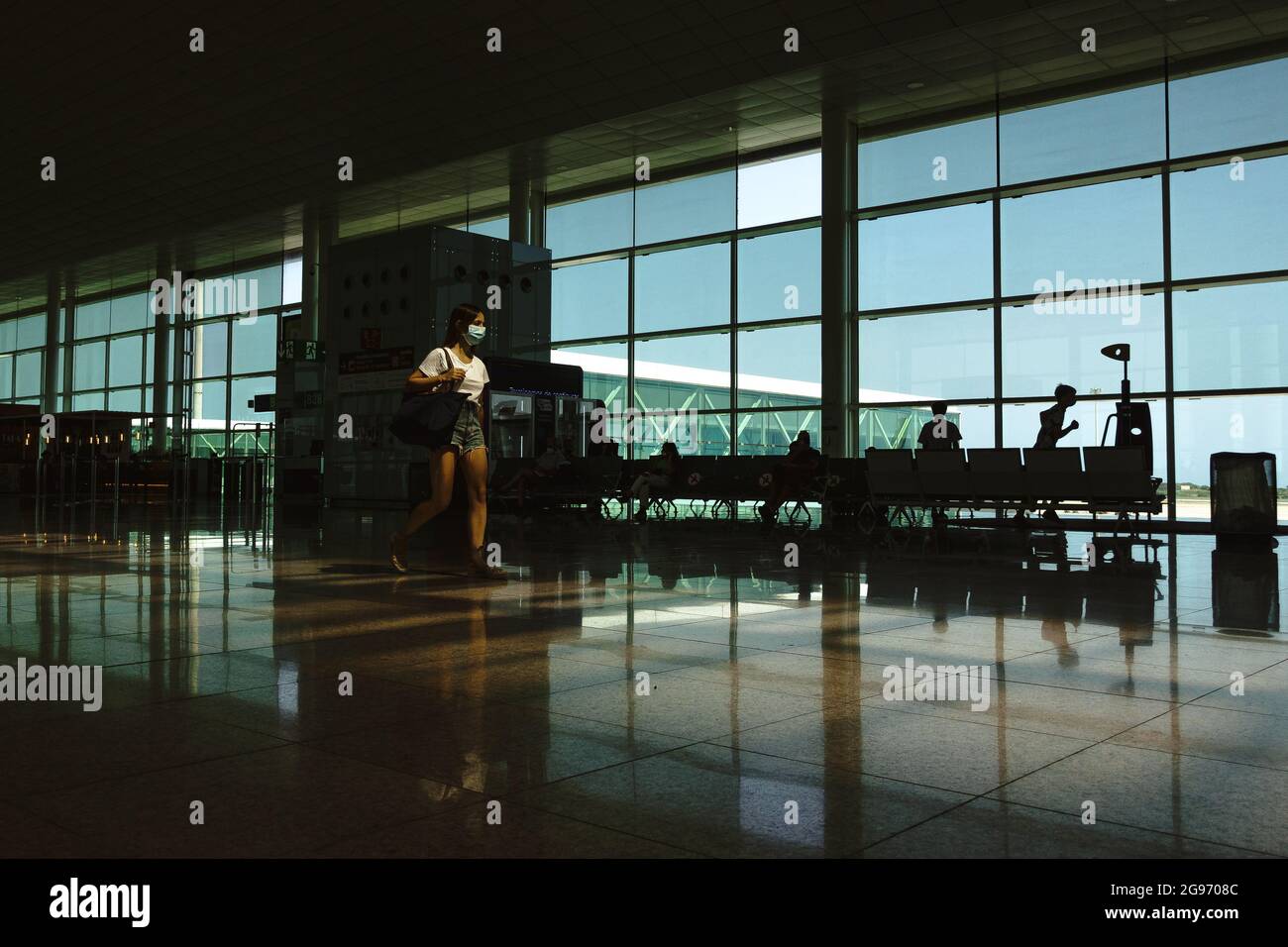 Barcelona, Spanien. Juli 2021. Ein Passagier, der eine schützende Gesichtsmask gegen die anhaltende Ausbreitung des Coronavirus trägt, geht an einem meist geschäftigen Terminal 1 am Flughafen von Barcelona vorbei, während Spaniens Tourismus einen weiteren Hit in die Liste der „hohen Inzidenz“ Deutschlands einträgt. Quelle: Matthias Oesterle/Alamy Live News Stockfoto