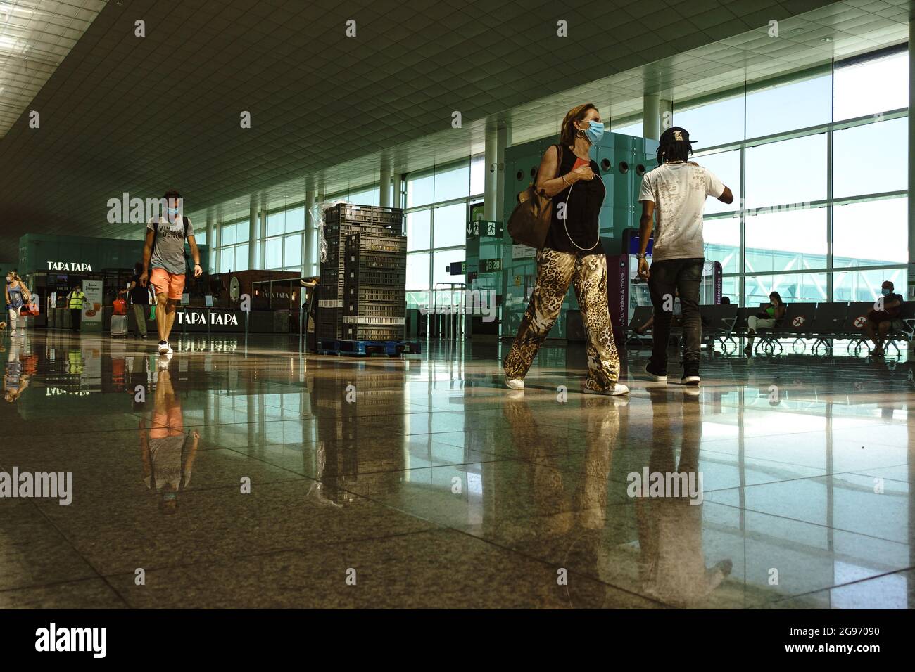 Barcelona, Spanien. Juli 2021. Passagiere, die eine schützende Gesichtsmask gegen die anhaltende Ausbreitung des Coronavirus tragen, gehen an einem meist geschäftigen Terminal 1 am Flughafen von Barcelona vorbei, da der spanische Tourismus einen weiteren Hit auf Deutschlands Liste der „hohen Inzidenz“ hinnimmt. Quelle: Matthias Oesterle/Alamy Live News Stockfoto