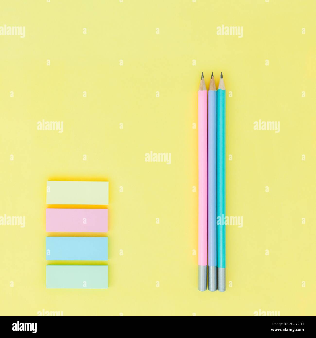 Dreifarbiger Bleistift und pastellfarbene Haftnotizen auf gelbem Papierhintergrund Stockfoto