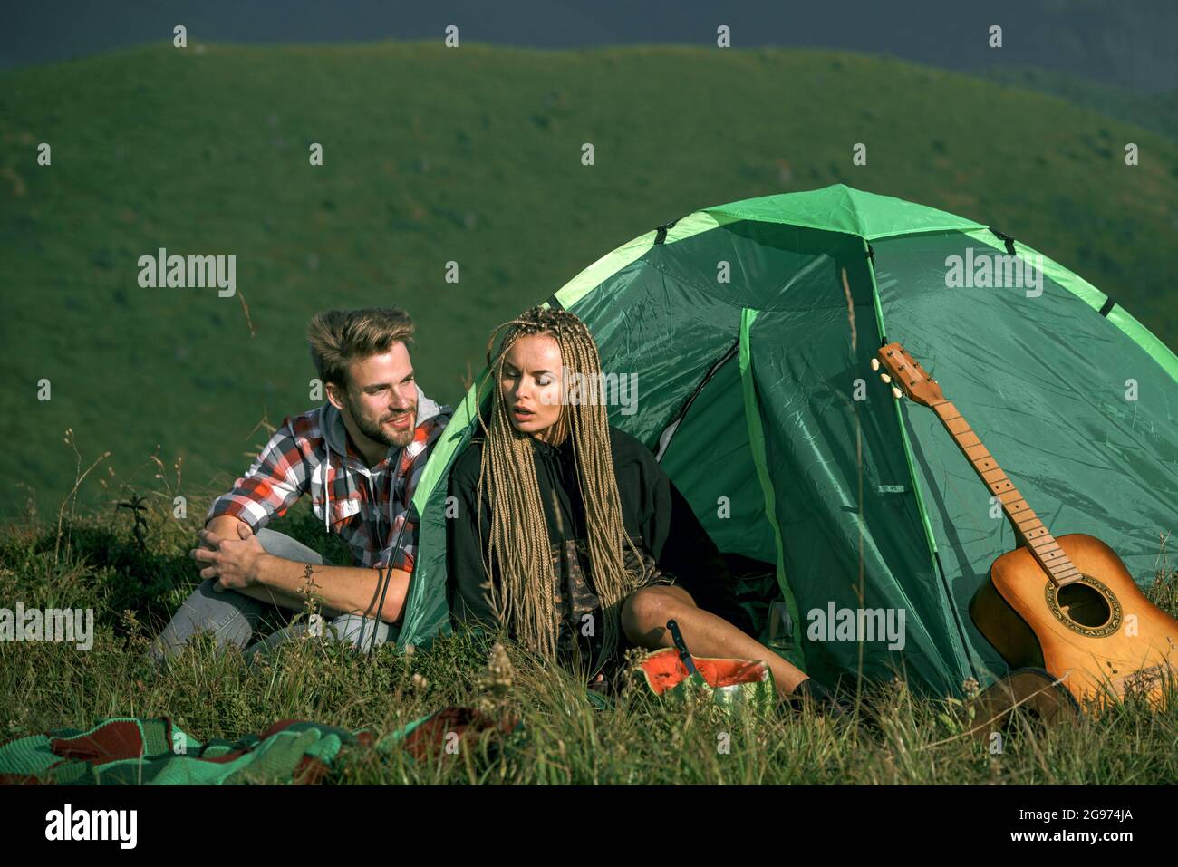 Junge Touristen. Verliebtes Paar, das in der Nähe des touristischen Zeltes im Wald sitzt. Paar lieben Reisen und Camping Stockfoto
