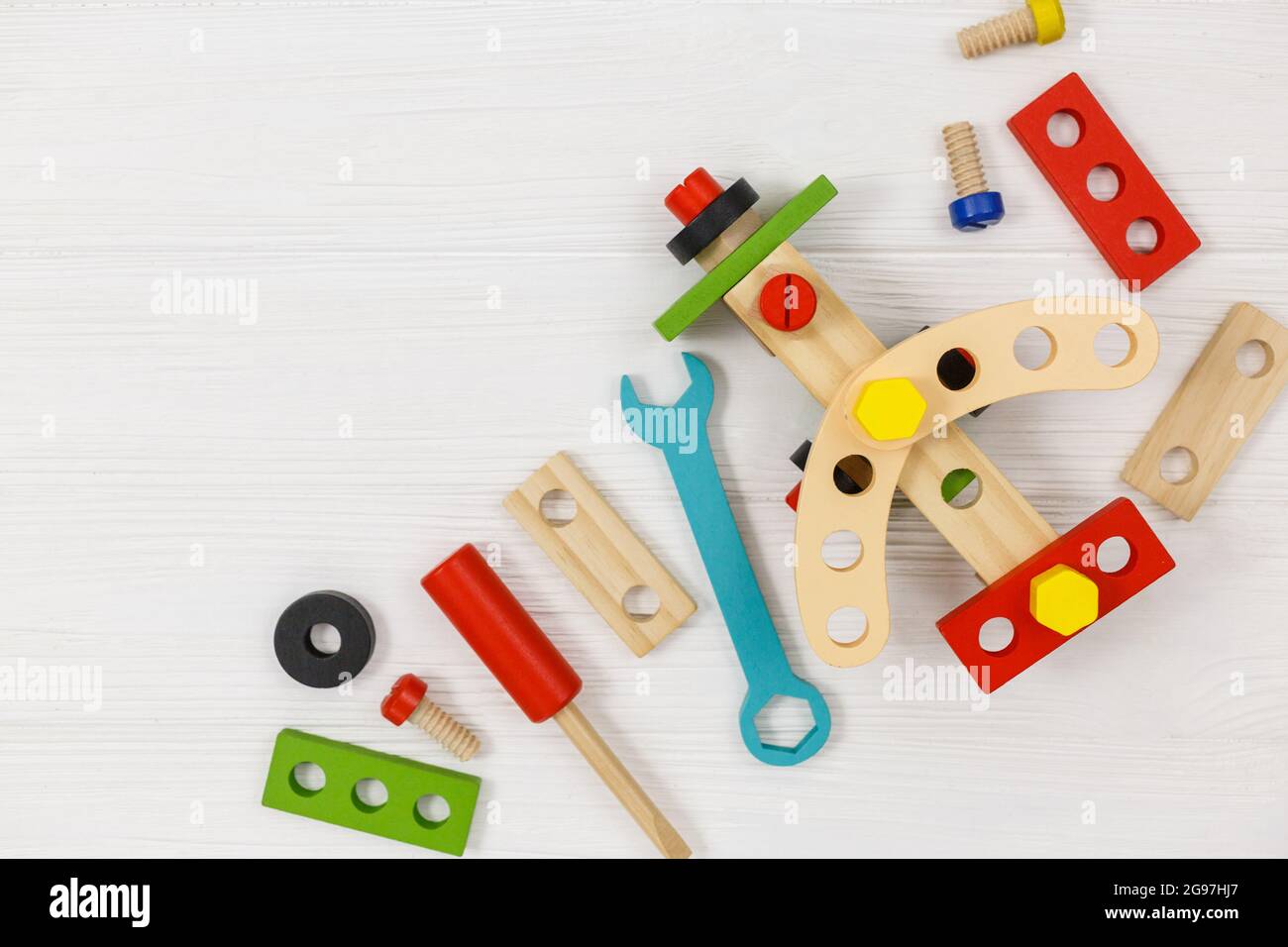 Ein farbenfroher Holzbausatz, Flugzeug für Kinder auf Holz. Set von Werkzeugen auf weißem Holztisch. Spiele und Werkzeuge für Kinder im Kindergarten, Vorschule Stockfoto