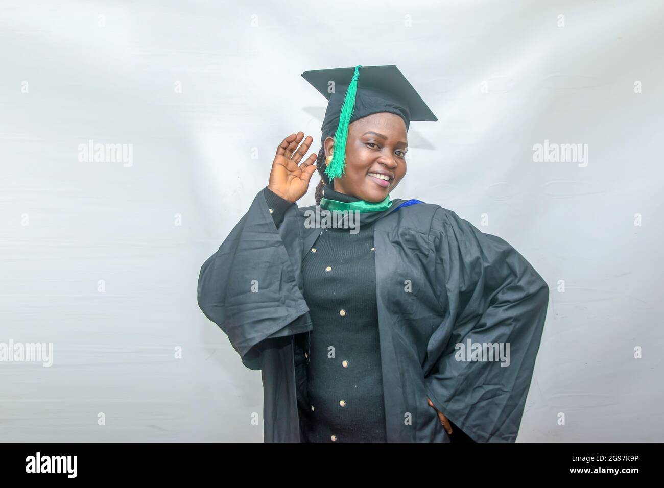 Stock-Foto einer afrikanischen Graduiertenin oder graduierenden Studenten, die ihren Körper freudig in ihrem schwarzen Graduierungsoutfit bewegen Stockfoto