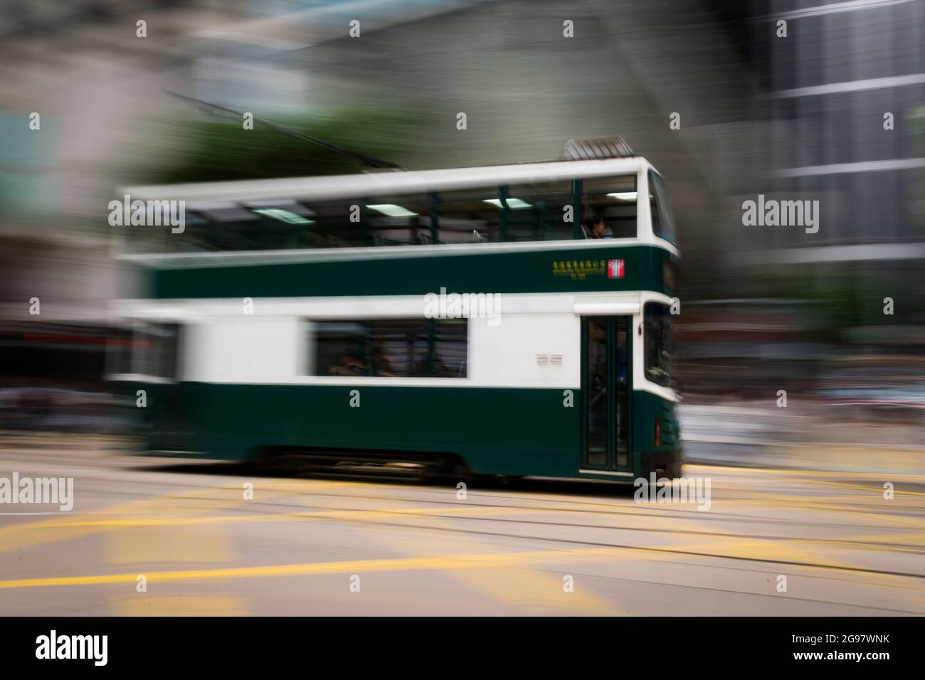 Eine Straßenbahn fährt entlang der des Voeux Road, Central, Hong Kong Island, in einer Schwenkaufnahme mit selektiven Bewegungsunschärfen aufgrund von Kamerabewegungen Stockfoto