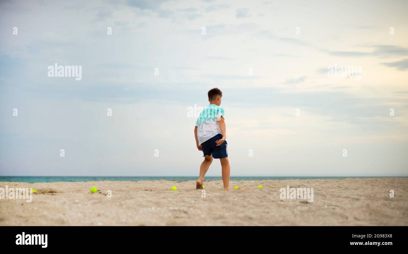 Junge Teenager, die am Sandstrand trainieren. Körperliches Training. Training zur Beinkoordination. Tennisbälle. Stockfoto