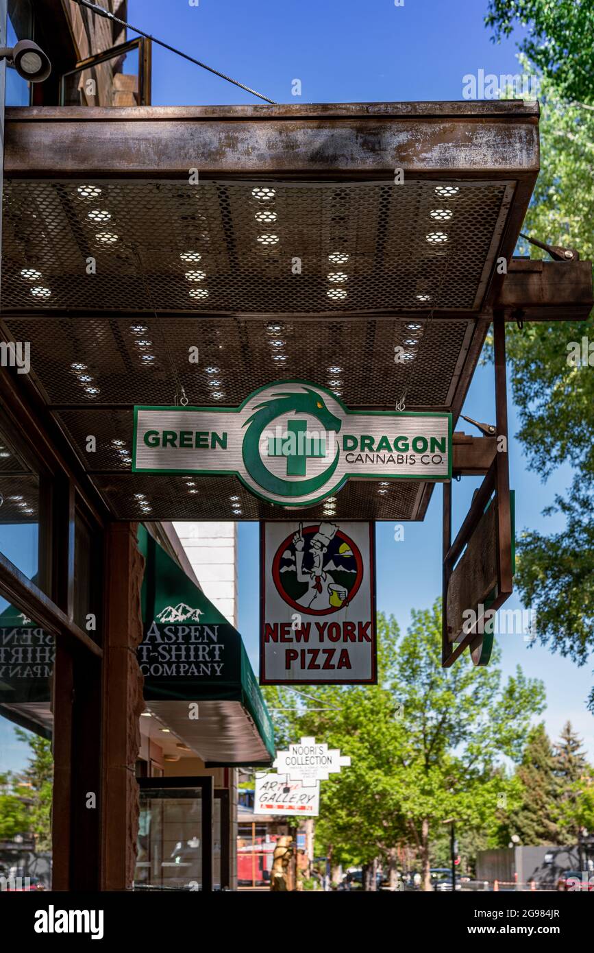 Schilder für Geschäfte und Restaurants, die Pizza und legales Marihuana verkaufen, hängen vom freitragenden Dach, das sich über den Bürgersteig in der Innenstadt von Aspen, Colorado, erstreckt. Stockfoto