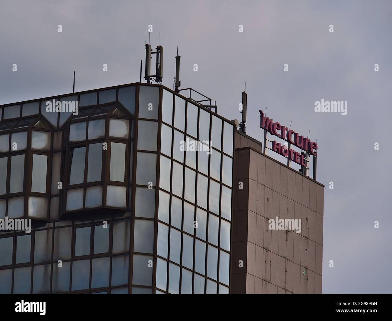 Oberer Teil des Mercure Hotels im Zentrum von Koblenz, Teil der französischen Accor S.A., in einem Gebäude mit Business-Logo und verwitterter Glasfassade. Stockfoto