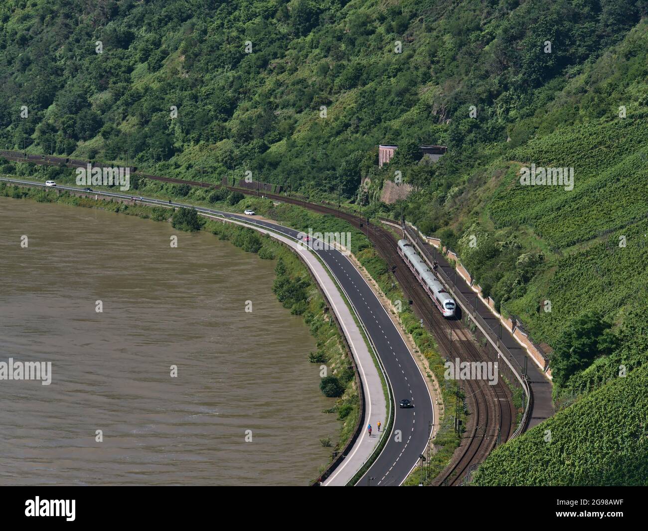 Luftaufnahme des Rheinufers mit Bahngleisen und dem ICE-Zug der Deutschen Bahn, der an sonnigen Tagen Autos auf der angrenzenden Straße vorbeifährt. Stockfoto