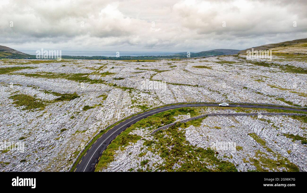 Luftaufnahme einer Straße, die durch den Burren in West-Irland führt, die aus Kalkstein bedeckten Bergen besteht. Stockfoto