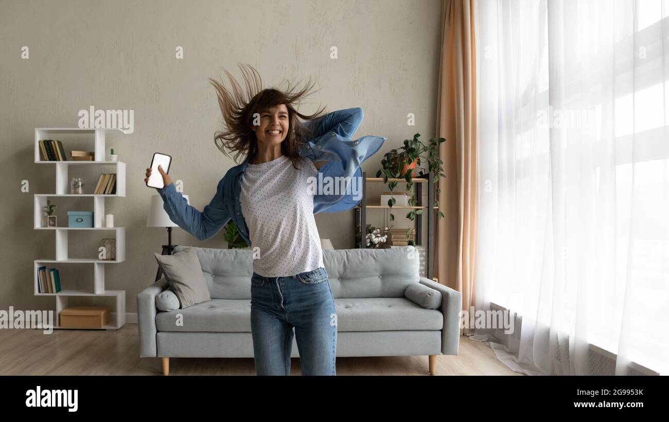 Fröhliche Frau tanzt hält Smartphone mit Mockup weißen Bildschirm Stockfoto