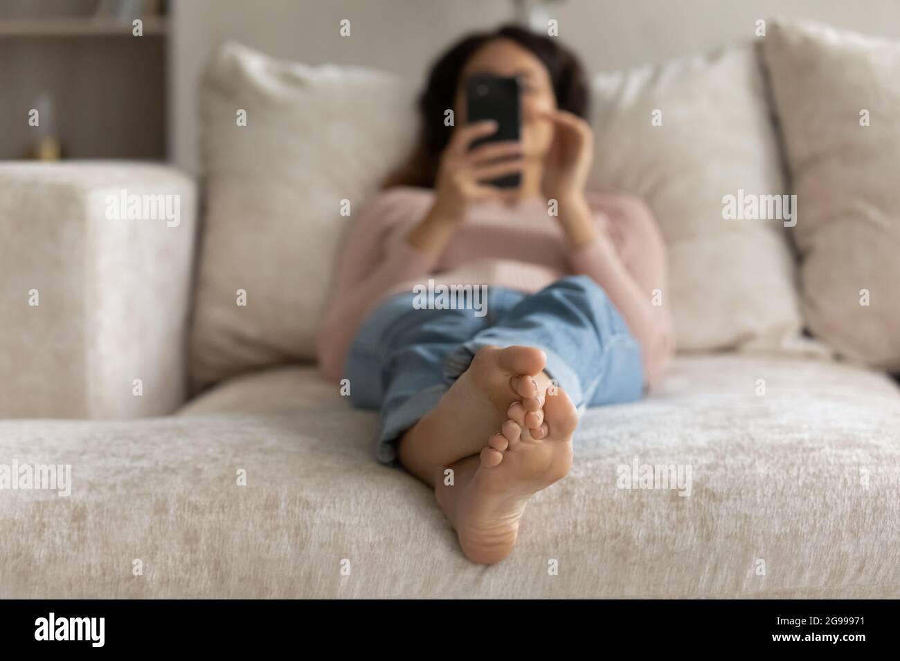 Nahaufnahme der Frau Entspannen Sie sich auf dem Sofa mit dem Smartphone Stockfoto