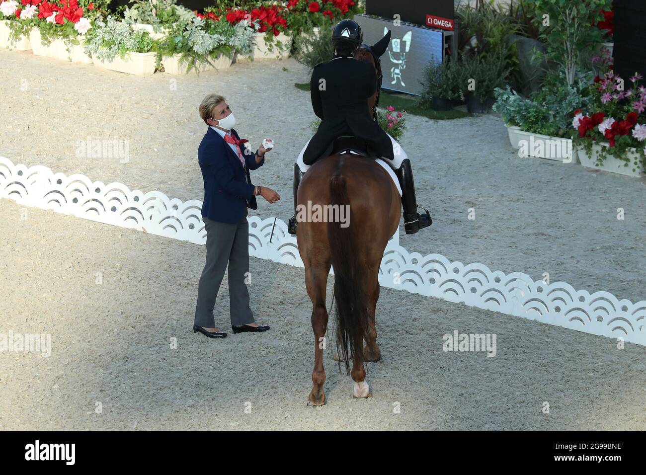 Tokio, Japan. Juli 2021. Pferdesport/Dressur: Olympia, Vorwettbewerb, Individuell, Grand Prix, Baji Koen Equestrian Park. Caroline Chew aus Singapur auf dem Pferd Tribiani muss den Wettbewerb unterbrechen. Ein Richter steht neben ihr und hält ein Taschentuch mit Blut in der Hand, das aus dem Maul des Pferdes kommt. Quelle: Friso Gentsch/dpa/Alamy Live News Stockfoto