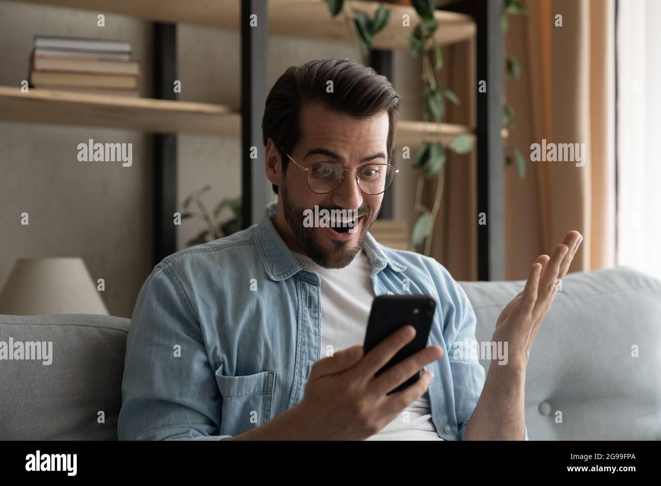 Mann hält Handy Gawp am Bildschirm lesen Nachrichten fühlt sich überrascht Stockfoto