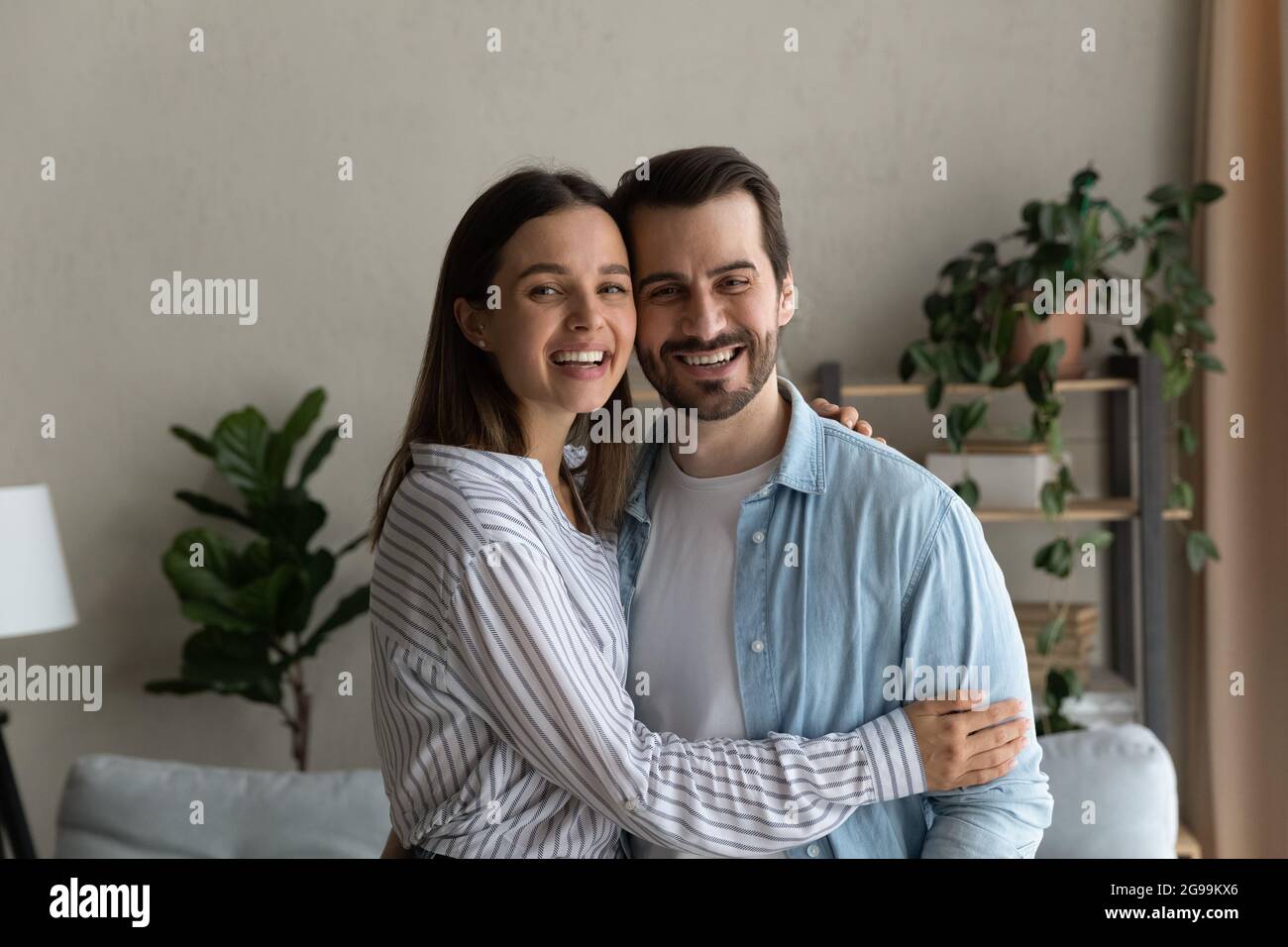 Fröhlich lachend verheiratetes Paar umarmt posiert im modernen Haus Stockfoto