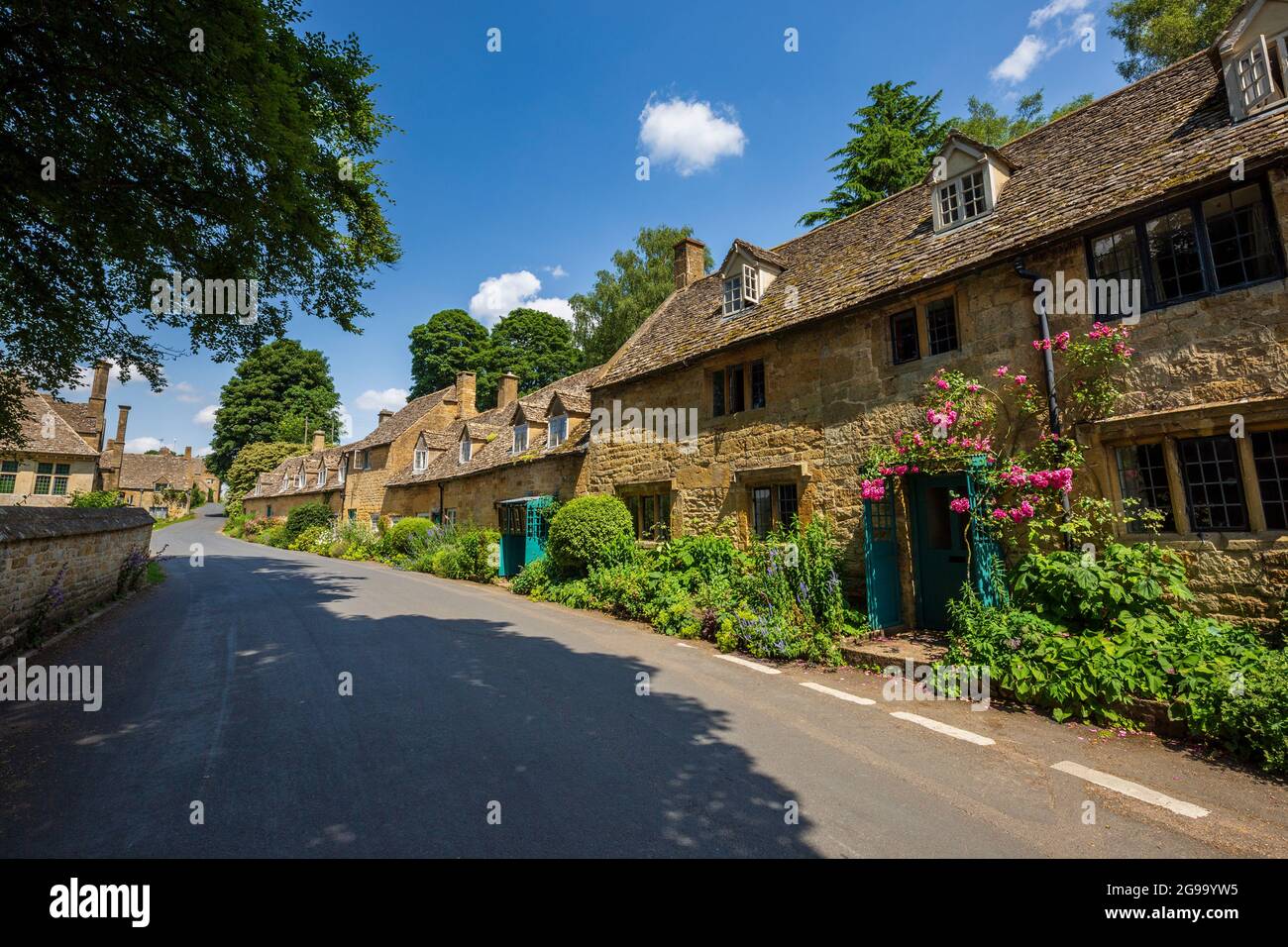 Cotswold Cotswold Cottages und Pink Roses auf der Straße durch Snowshill Village, Gloucestershire, England Stockfoto