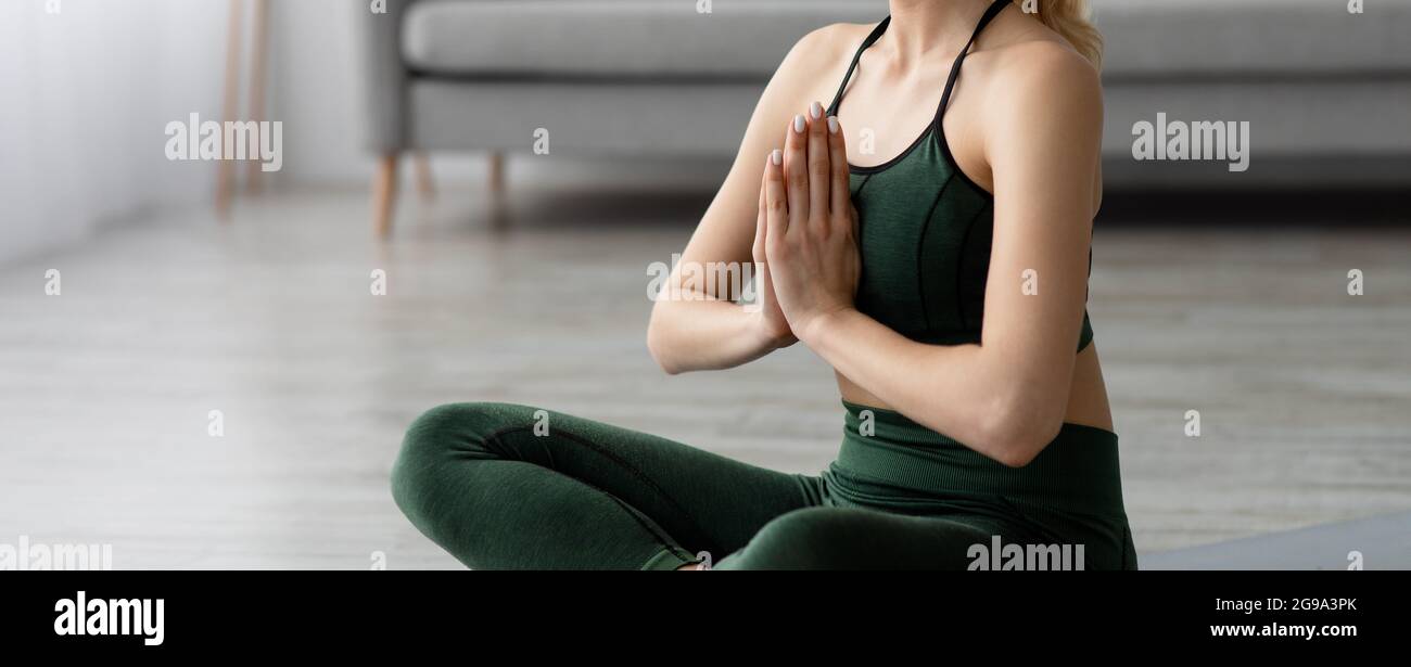 Junge blonde, gesunde, schöne Frau in Sportkleidung, die zu Hause Yoga praktiziert und in Lotuspose sitzt Stockfoto